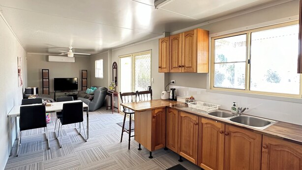 Une cuisine moderne avec des meubles en bois, un coin repas comprenant une table et des chaises, et une grande fenêtre qui laisse entrer la lumière naturelle.