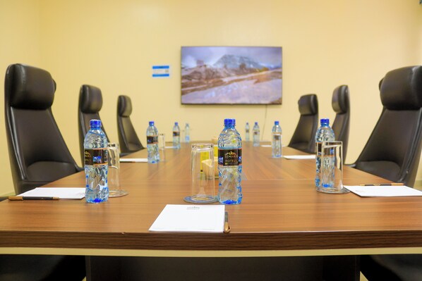 A conference room with a long table, black chairs, water bottles, glasses, and a framed picture on the wall.