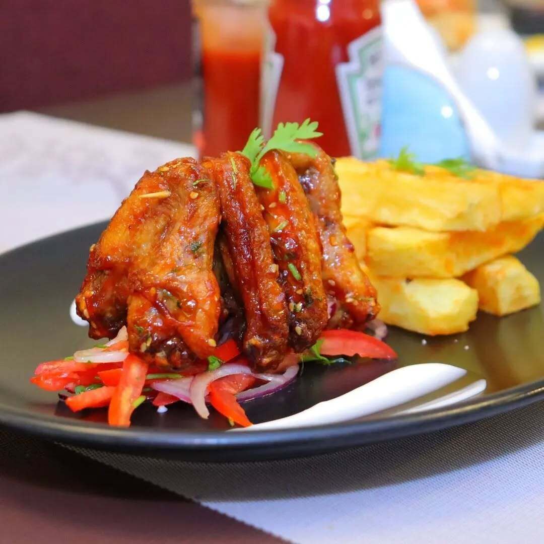 A plate of chicken wings with a side of fries and a fresh salad.