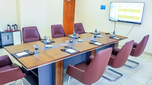 A conference room with a long table, multiple chairs, water bottles, and a presentation screen. - Semara Hotels Machakos (Machakos)