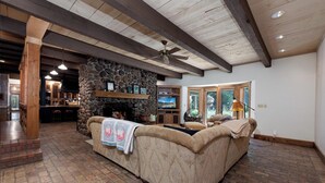 A cozy living room with a stone fireplace, a large sofa, and a television.
