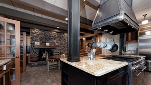 A kitchen with a stone wall, a fireplace, and a stainless steel range hood.