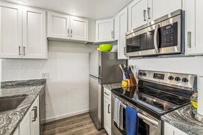 A modern kitchen with white cabinets, stainless steel appliances, and granite countertops.