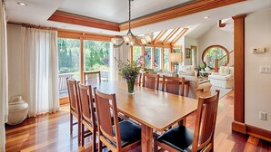Un comedor amplio con una gran mesa de madera y sillas, rodeado de ventanas grandes que ofrecen vistas al exterior.