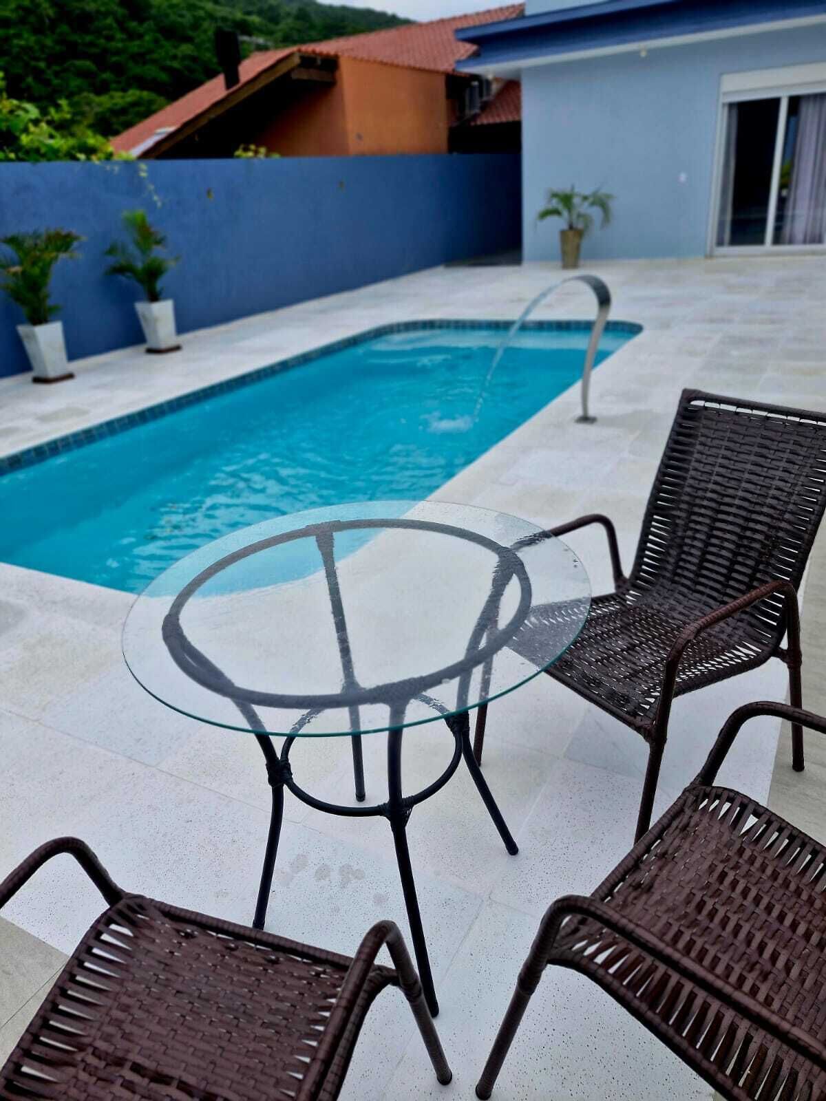 Une piscine avec une table en verre et des chaises en osier.