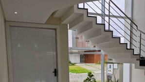 A modern interior with a wet floor, a white door, and a staircase leading to an upper level.