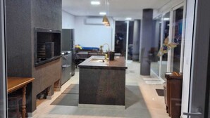 A modern kitchen with a central island, dark cabinetry, and a tiled floor.