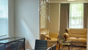 A modern living room with a dining area, featuring a chandelier, leather sofas, and a glass coffee table. - Newly renovated luxurious and private, 3-bedroom 2 bath West Side Oasis! (Buffalo)