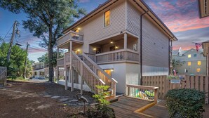 Uma casa de dois andares com varanda, escada e deck.