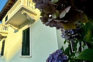 A building with a light facade and green shutters, featuring a balcony with ornate railings. - Suite 3, Villa Patrizia Guesthouse (Como)