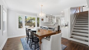 Una cocina amplia con una mesa de comedor de madera, armarios blancos y una escalera que sube a un nivel superior.