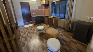 Una cocina compacta con suelo de madera, un lavamanos integrado y una ventana con cortinas.