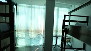 Habitación con literas, una ventana grande, una silla y una mesa.