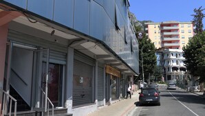 Un edificio moderno con fachada de vidrio, entrada visible con escalones y cielo despejado.