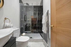 A modern bathroom with a glass-enclosed shower, a white toilet, and a vanity with a sink.