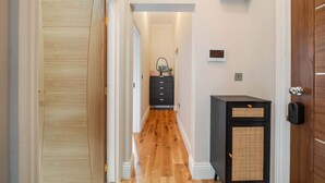 Un couloir doté d’un plancher en bois, d’une armoire noire et d’une porte avec une poignée.