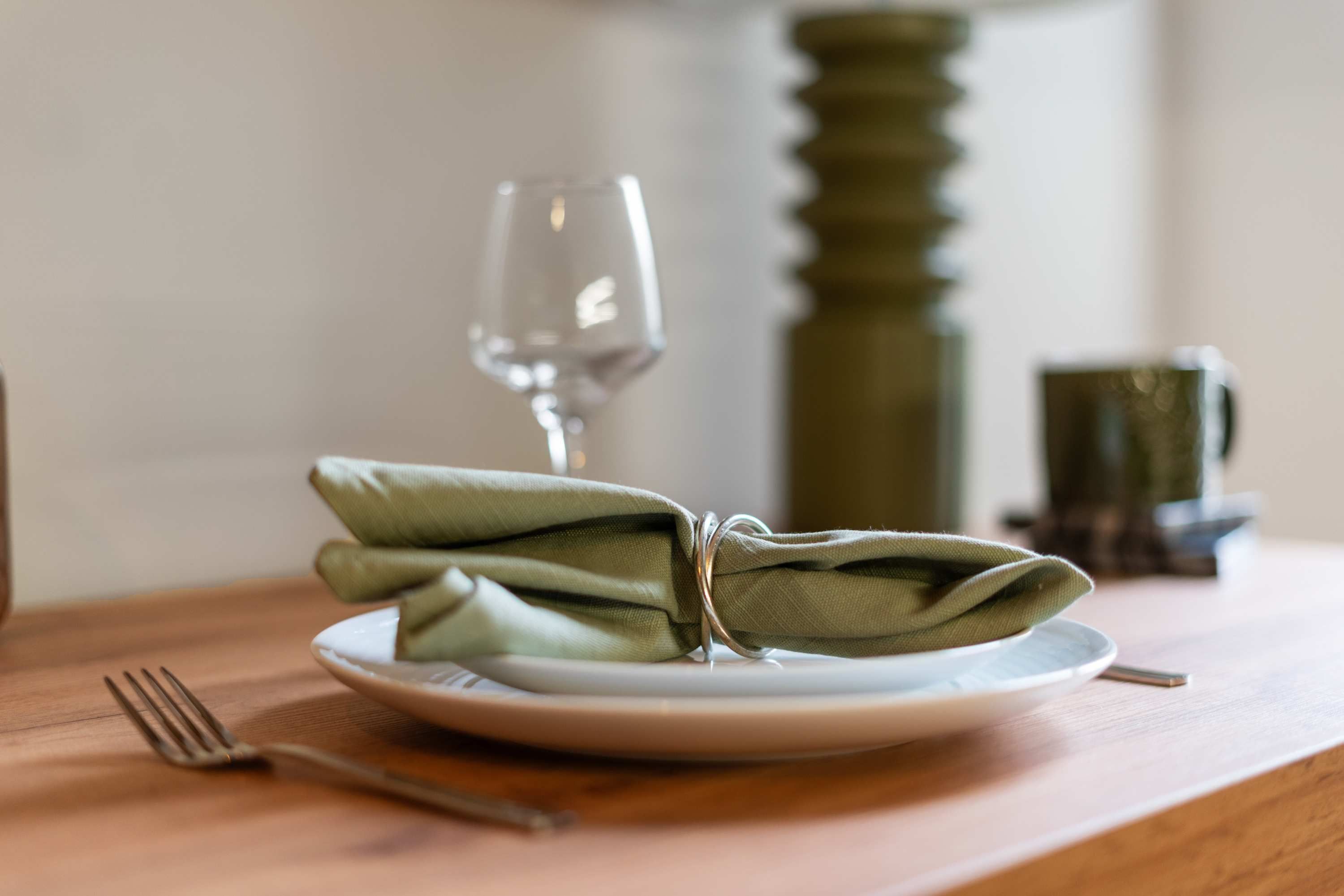 A plate with a folded napkin and a fork on a wooden table.