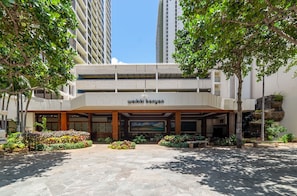 A modern building with a sign reading 'walki kiban.' It features a covered entrance, outdoor seating area, and is surrounded by greenery.