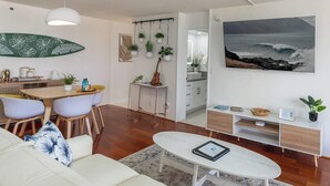 Ein modernes Wohnzimmer mit Sofa, Couchtisch, Essbereich und einer Küche im Hintergrund.