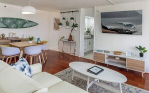 Ein modernes Wohnzimmer mit Sofa, Couchtisch, Essbereich und einer Küche im Hintergrund.