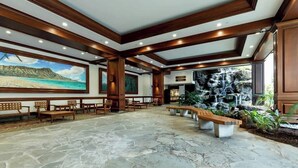 Eine geräumige Lobby mit Steinböden, hölzernen Bänken und einem Wasserfall.
