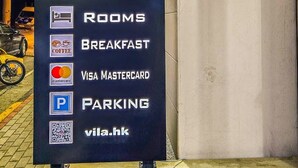 Schild für Vila HK, mit Auflistung von Annehmlichkeiten wie Zimmern, Frühstück, Parkplatz und Akzeptanz von Visa und MasterCard.