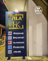 Placa de Vila HK, indicando comodidades como quartos, café da manhã, estacionamento e aceitação de Visa e MasterCard.