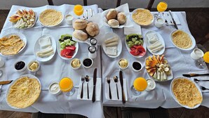 Ein Tisch für zwei Personen, gedeckt mit verschiedenen Frühstücksleckereien wie Brot, Früchten und Getränken.