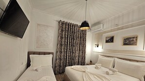 Ein Hotelzimmer mit zwei Betten, einem Fernseher, einem Deckenventilator und einem Fenster mit Vorhängen.