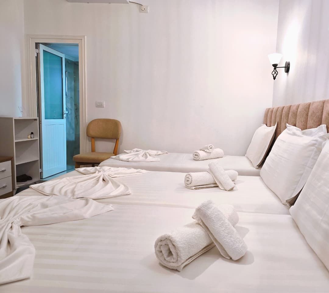 Quarto de hotel com duas camas, uma cadeira e um guarda-roupa.