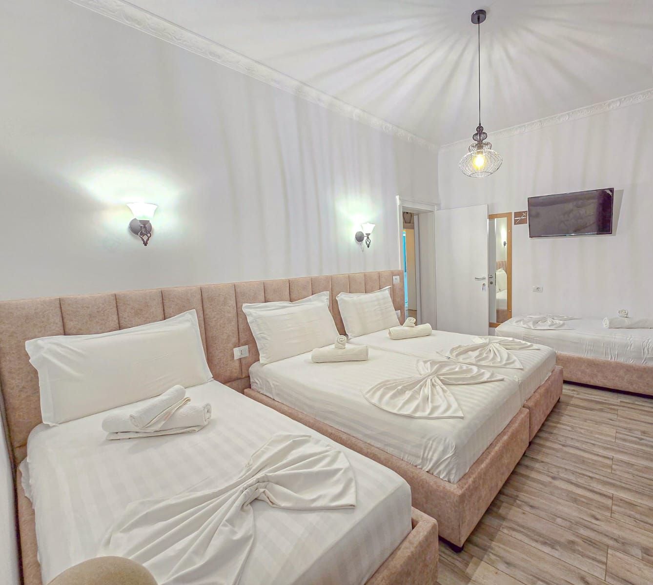 A hotel room with two beds, a television, and a chandelier.