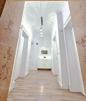 A hallway with a white vanity, a hanging light fixture, and a mirror above it. - Vila Hk (Krujë)
