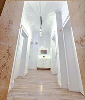 Um corredor com uma toucador branca, uma luminária pendente e um espelho em cima.