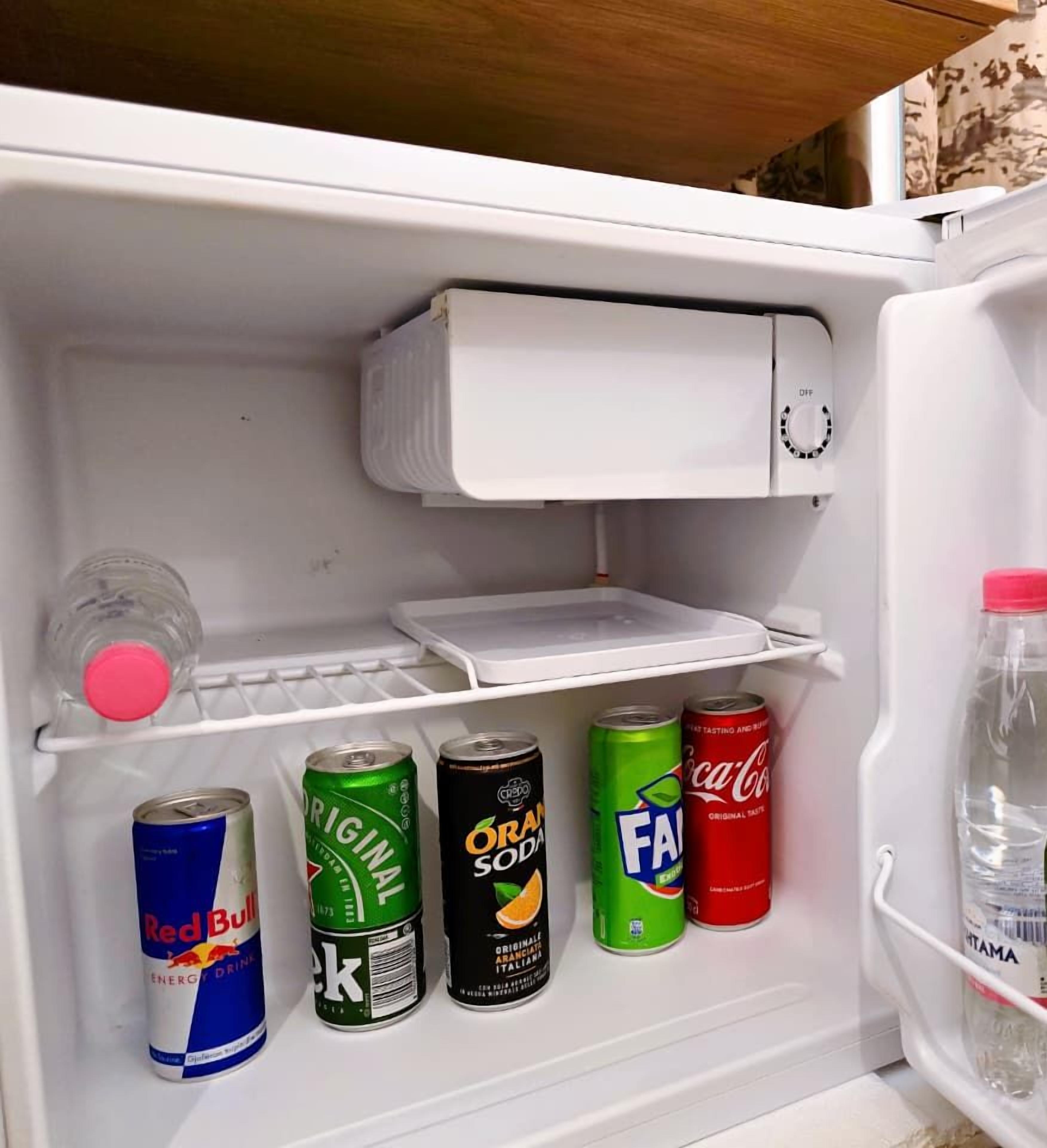 A refrigerator with a shelf containing various beverages including energy drinks, soda, and beer.