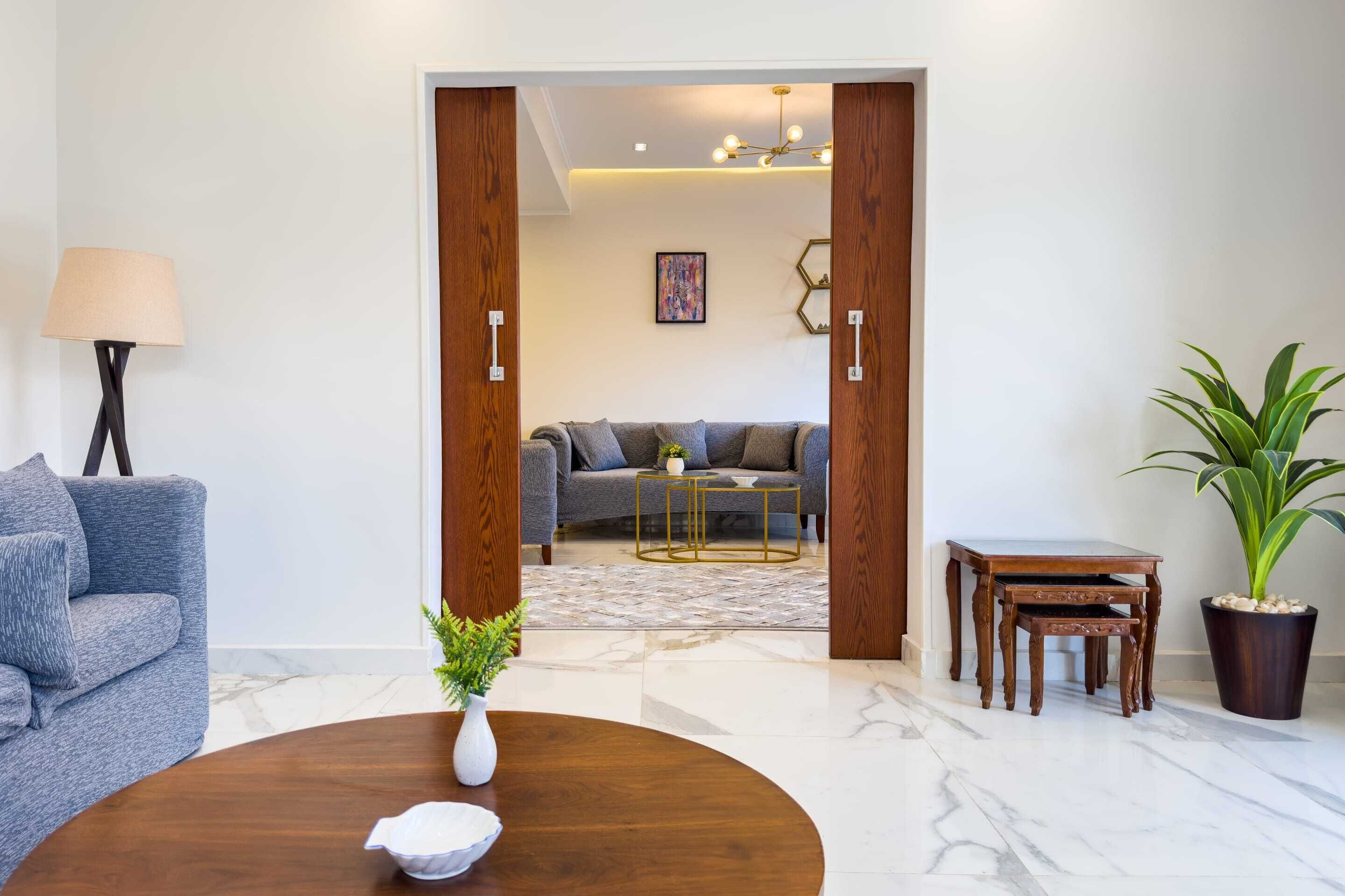 Una sala de estar moderna con un sofá gris, una mesa de centro de madera y una planta en maceta.