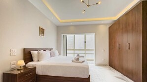 A bedroom with a large bed, wooden wardrobe, and a nightstand with a lamp.