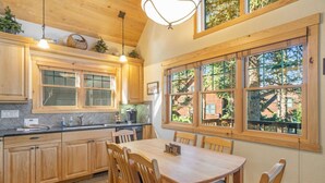 Una cocina con armarios de madera, una mesa de comedor y ventanas amplias.