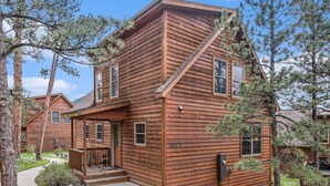 A wooden cabin with a porch, a small front yard, and a clear sky. - Wildlife, shared hot tub, fireplace, deck, BBQ! (Estes Park)