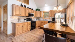 A modern kitchen with wooden cabinets, stainless steel appliances, and a large island. - Upstairs AC! Fireplace, deck, BBQ, shared hot tub (Estes Park)
