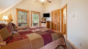 A bedroom with a large bed, a ceiling fan, a TV, and a wooden wardrobe.