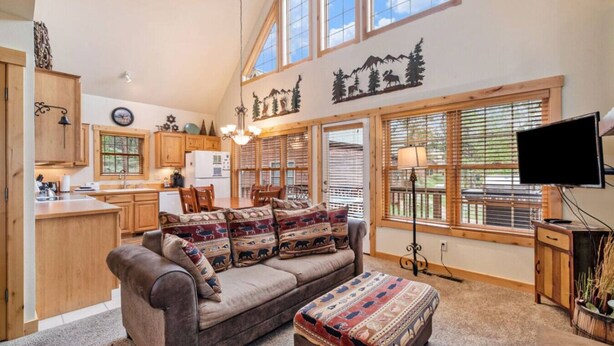A cozy living room with a sofa, ottoman, and a large window with blinds.