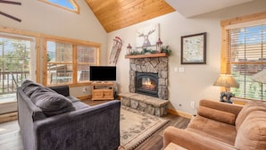 A cozy living room with a stone fireplace, wooden ceiling, and large windows. - Best views! Deck, fireplace, BBQ, shared hot tub! (Estes Park)