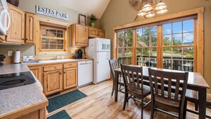 Una cocina con armarios de madera, un refrigerador blanco y una zona de comedor con mesa y sillas.