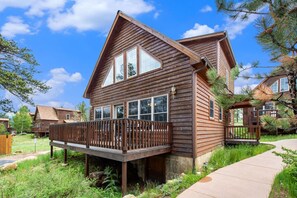A wooden cabin with a deck, large windows, and a clear sky. - AC, K beds, views, shared hot tub, BBQ, deck (Estes Park)