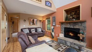 A cozy living room with a stone fireplace, a leather sofa, and a wooden floor. - Panoramic RMNP Views. K beds, deck, fireplace, BBQ (Estes Park)