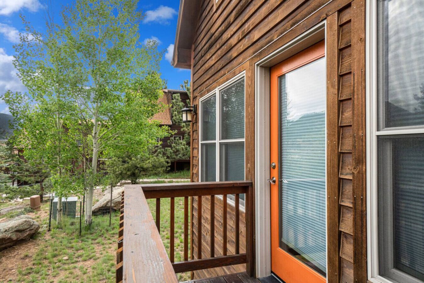 A wooden cabin with a deck, large windows, and a door.
