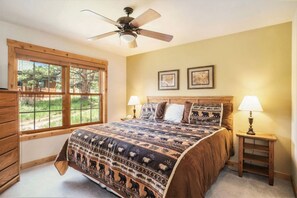A bedroom with a large bed, two bedside lamps, a ceiling fan, and a window with a view of greenery. - Cabin, views, K bed, shared hot tub, BBQ, deck! (Estes Park)