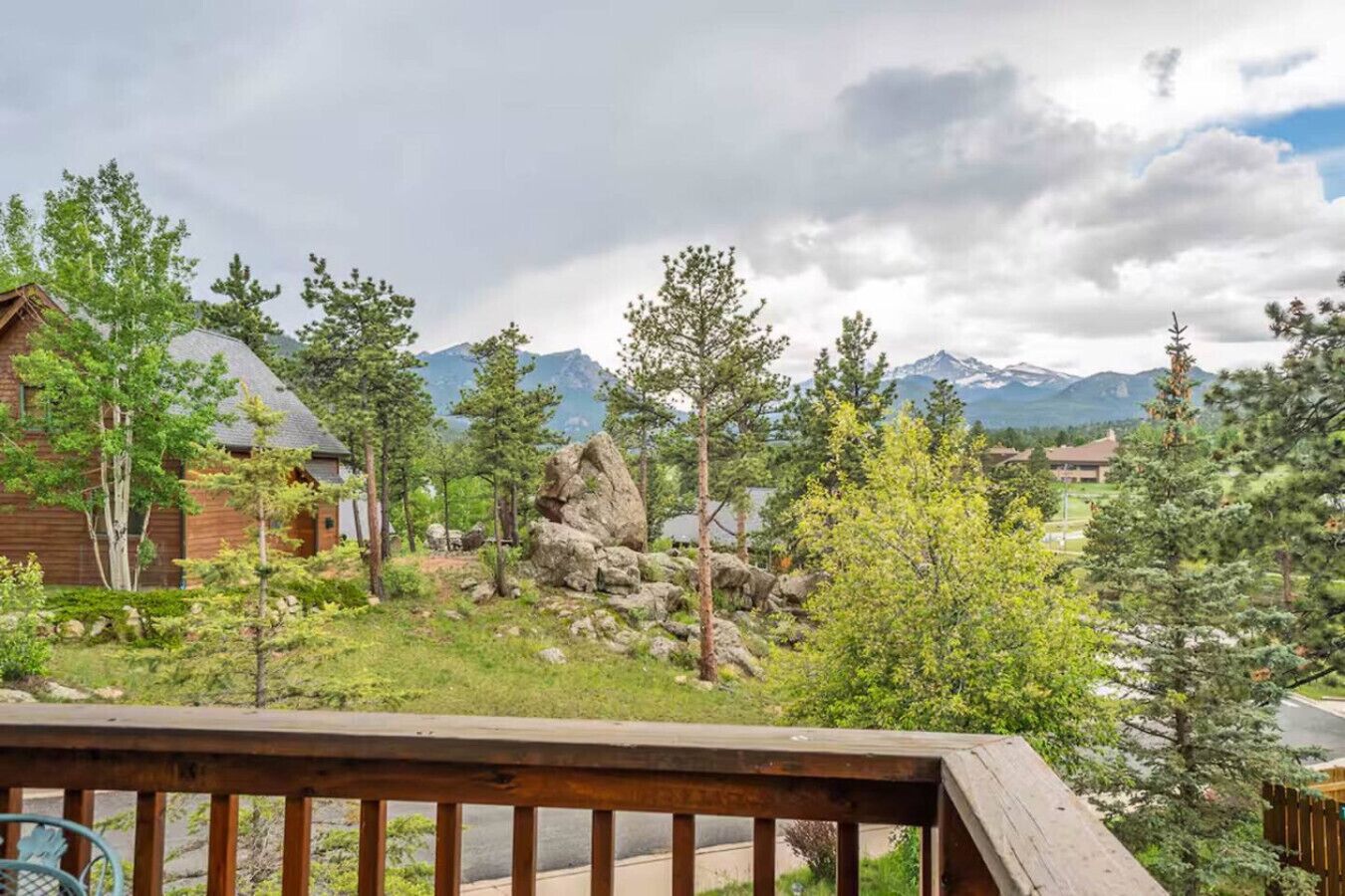 A wooden deck overlooking a mountainous landscape with trees and a cabin.