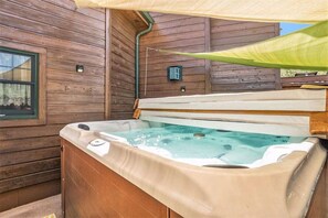 A hot tub in a wooden cabin with a window and a green canopy.