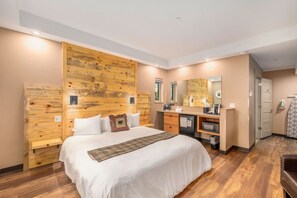 A hotel room with a large bed, wooden headboard, a small desk with a mirror, and a wardrobe.
